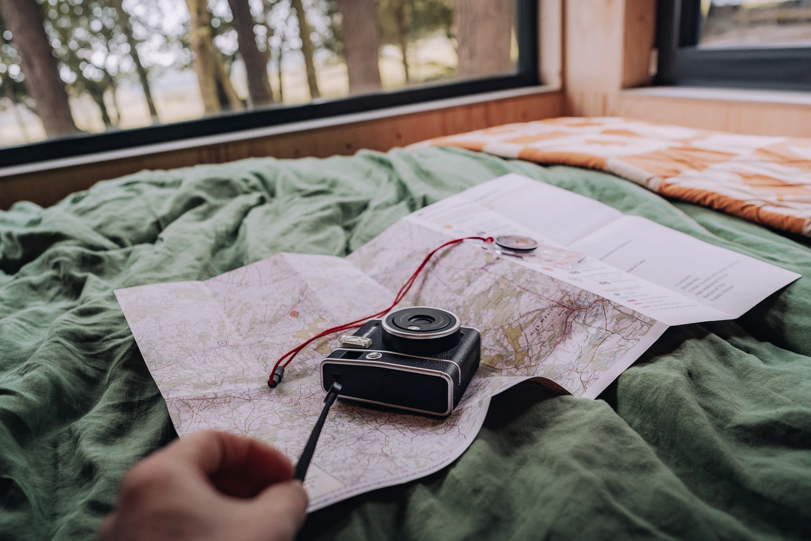 Camera and map on the bed inside the Unplugged Mabel cabin