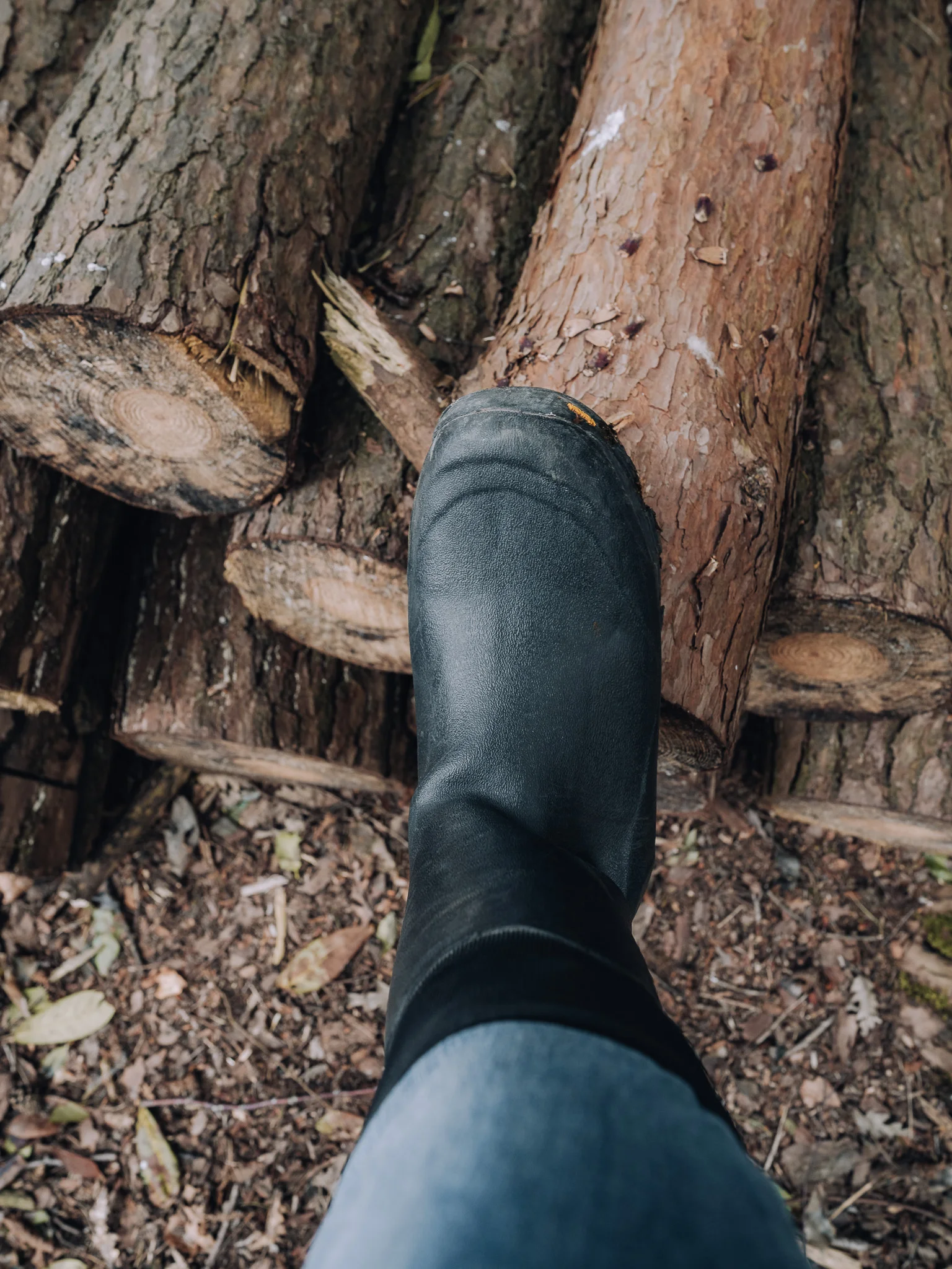 Man wearing wellies standing on logs collected for the fire at the Unplugged Mabel cabin