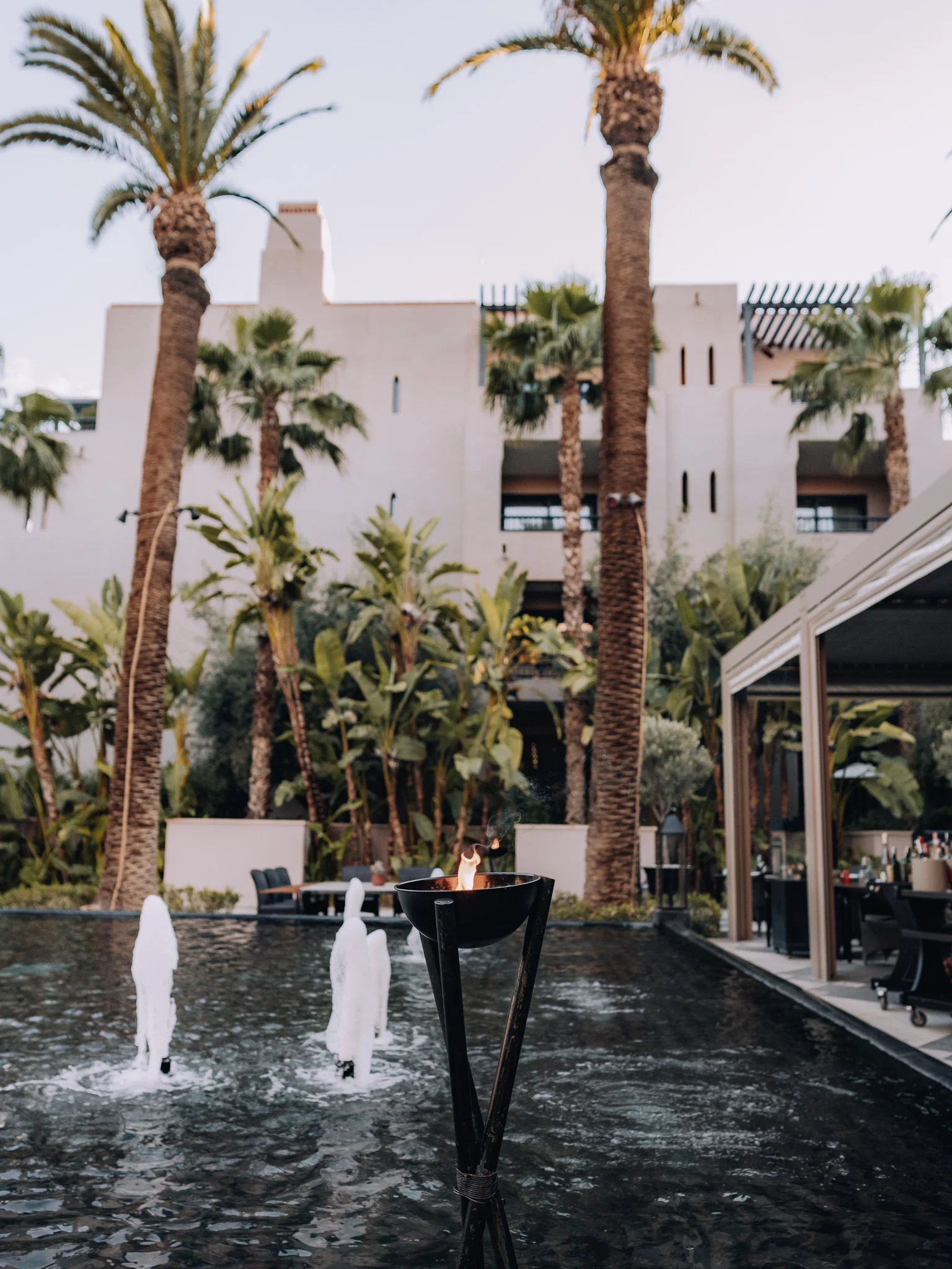Quattro restaurant exterior with pond and flaming candle at Four Seasons Marrakech