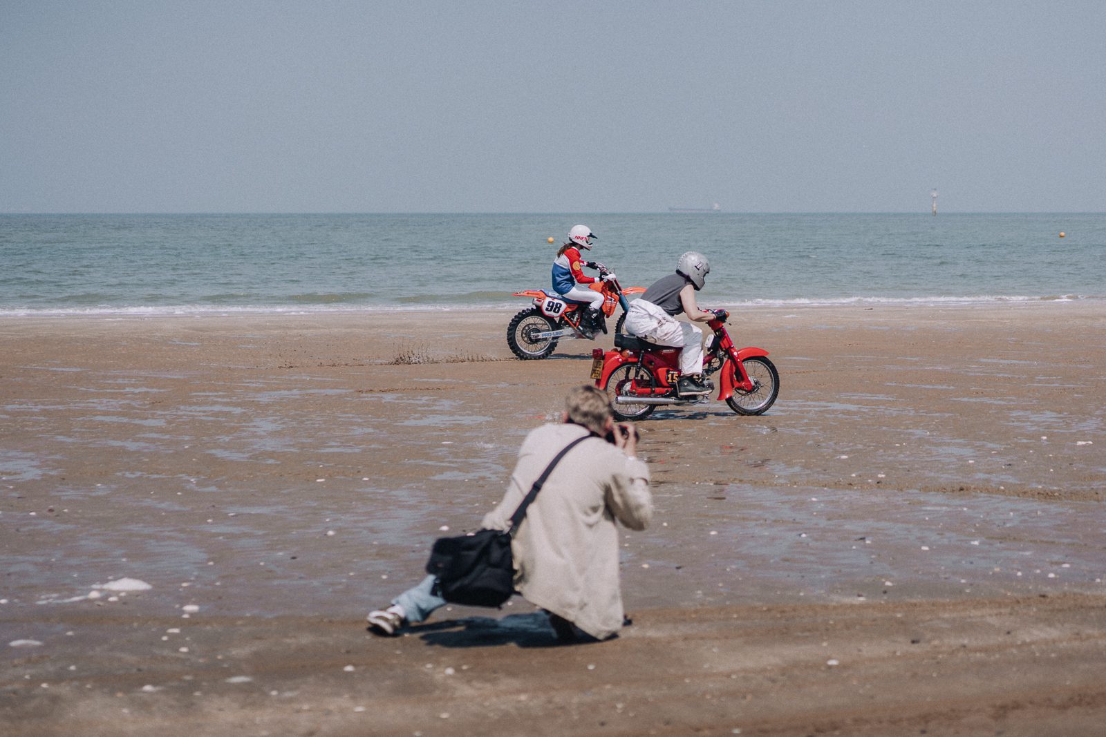 Photographer captures two motorcyclists on a sandy beach.
