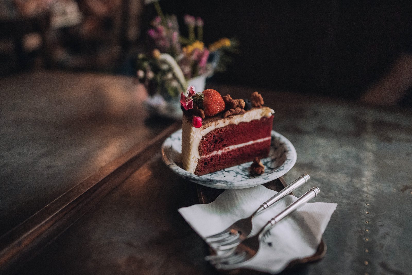 Slice of red velvet cake on a decorative plate.