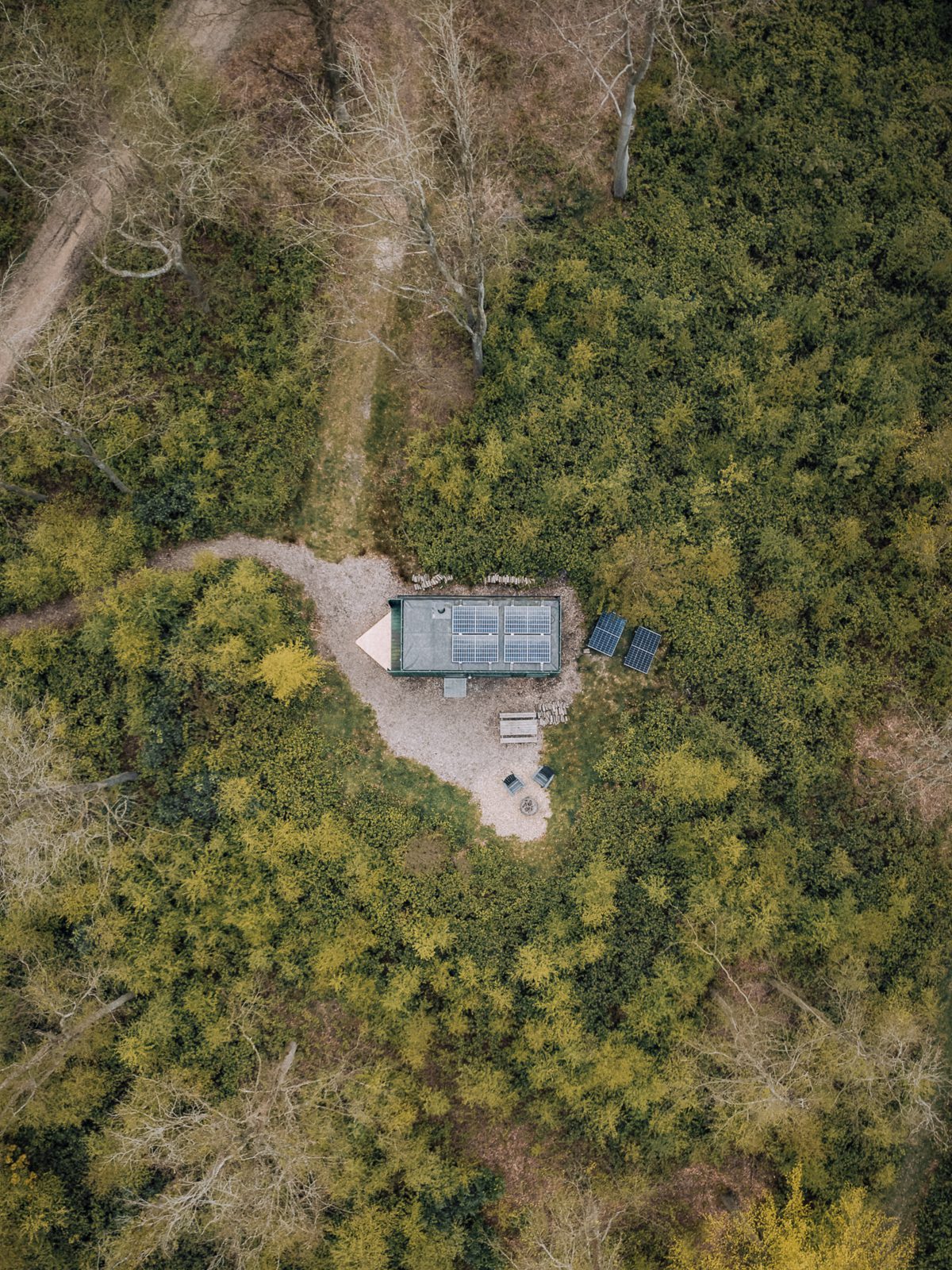 An aerial shot of an off grid cabin in the woods.