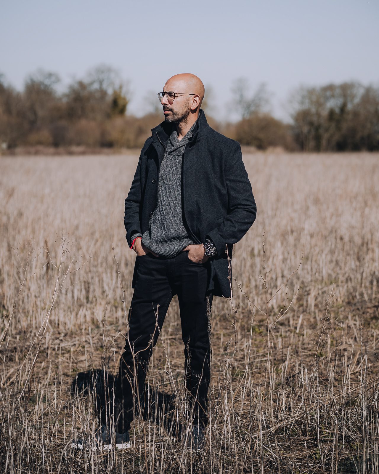 Man in dark clothes stands in a field.