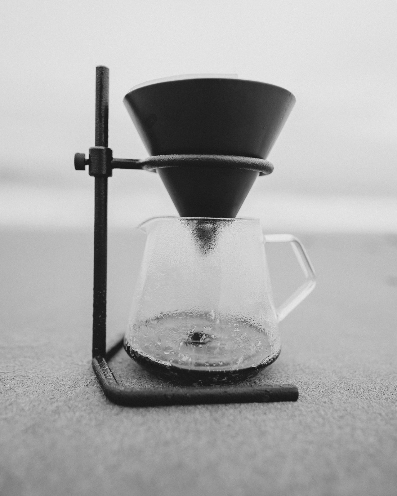 A drip coffee on a sandy beach.