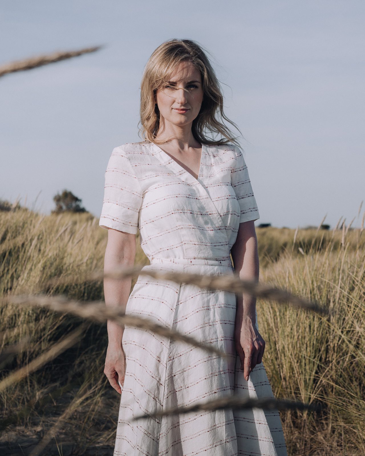 Woman in white dress standing in long grass.