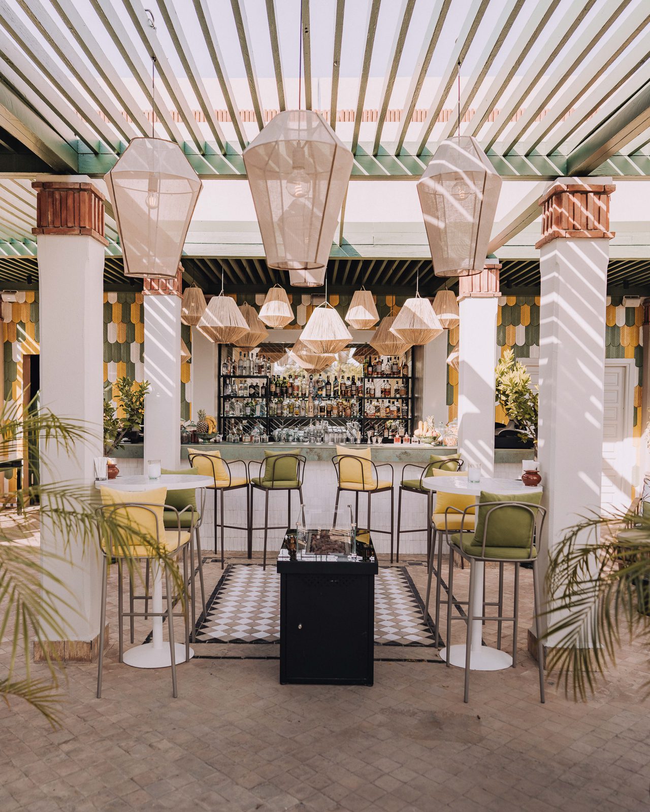 Trendy outdoor bar. Natural pendants lights hanging over the green and yellow seating.
