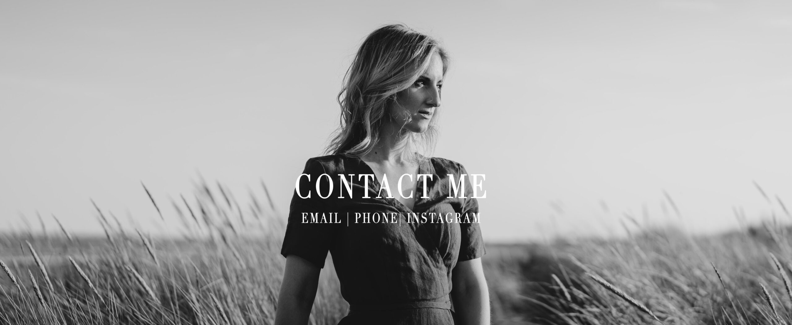 Black and white image of a woman standing in long grasses