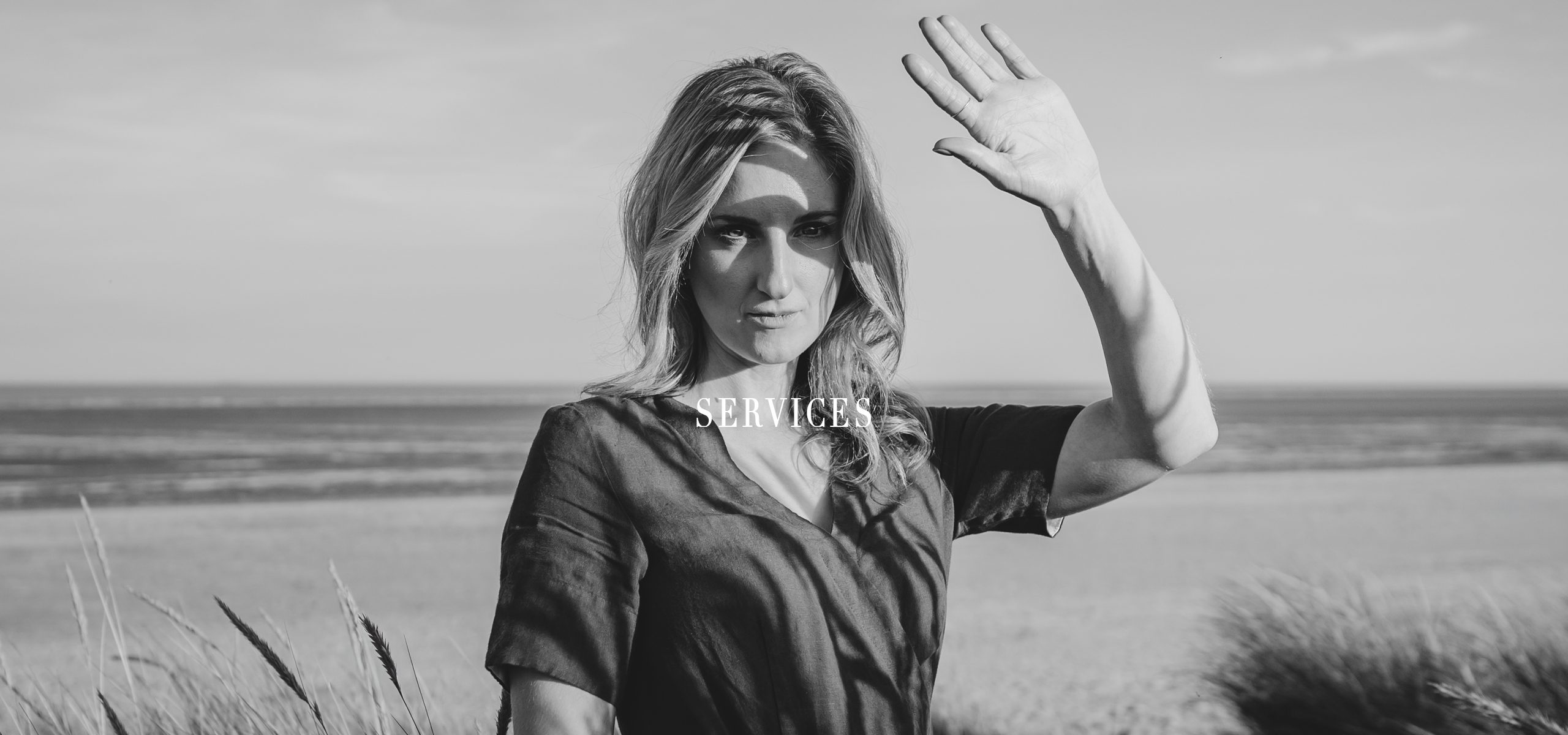 Black and white image of a woman on a sandy beach.