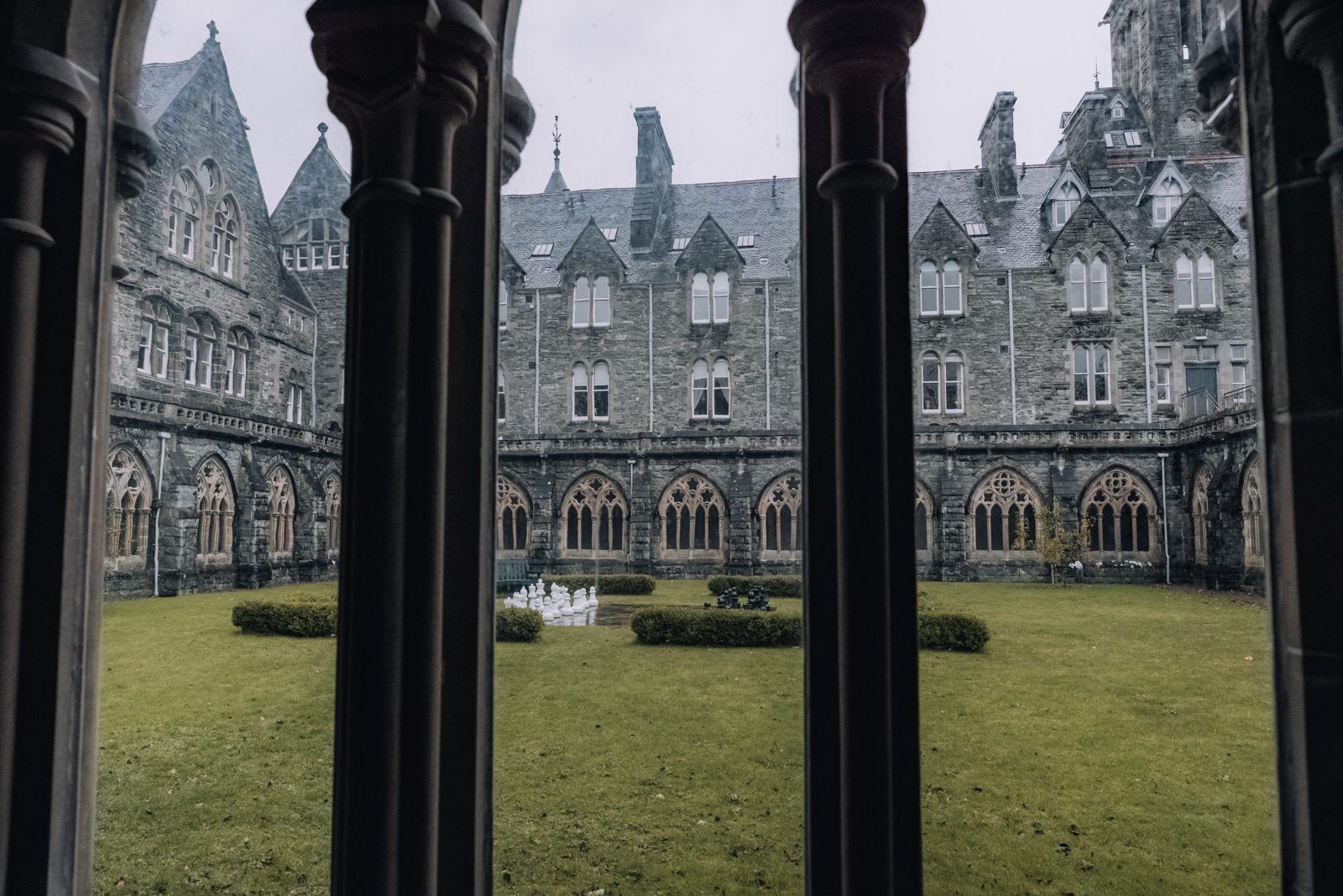 Gothic architecture surrounding a courtyard with a giant outside chess board.