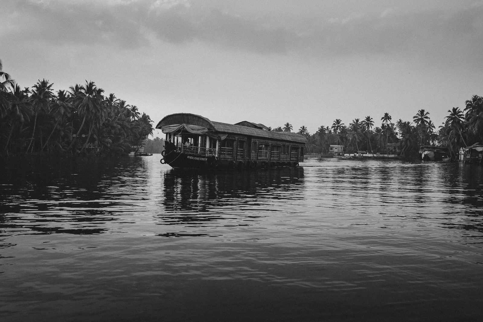 Houseboat cruising through the peaceful backwaters of Alleppey, Kerala, India, surrounded by palm-lined canals.