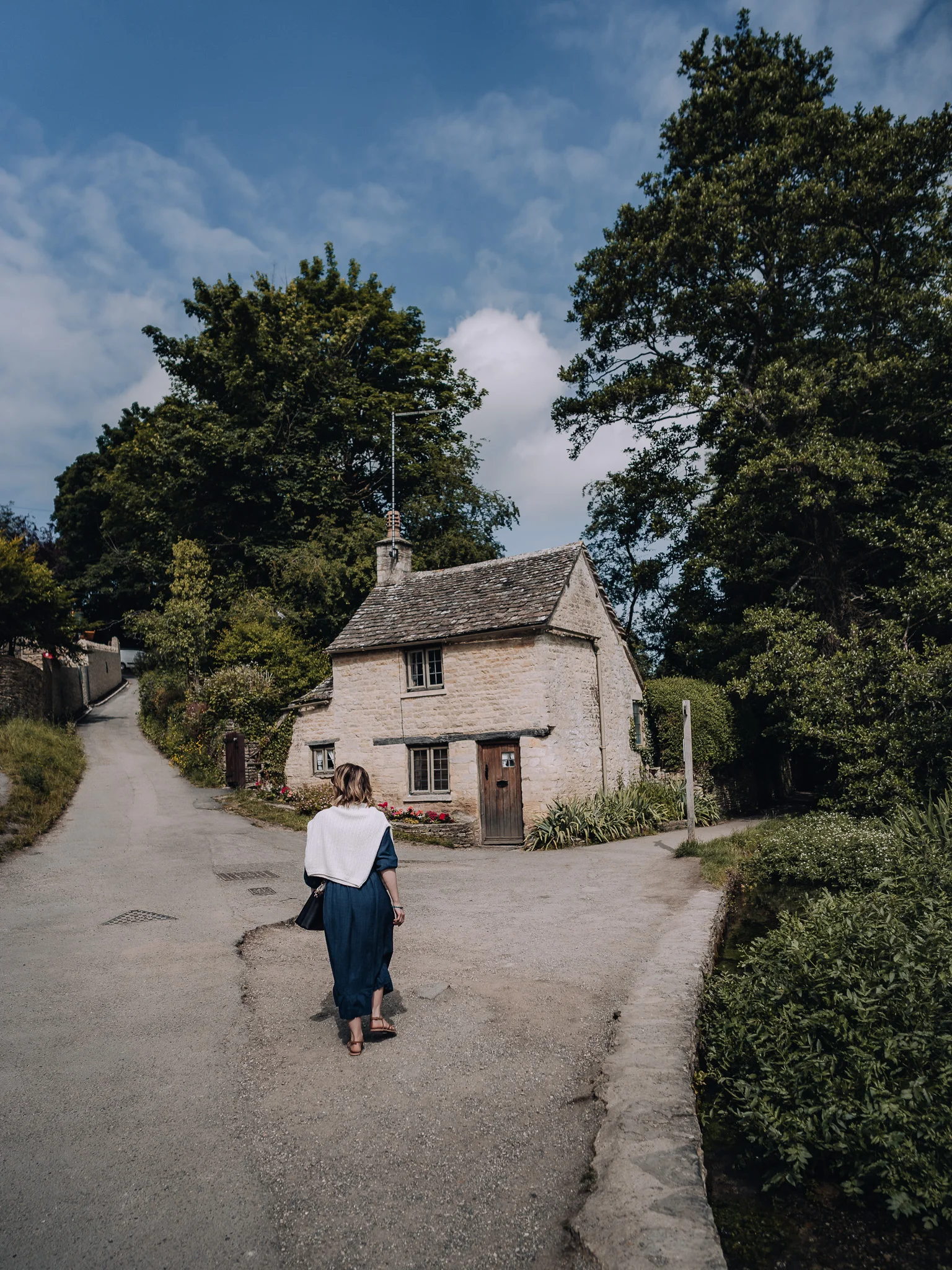 Female walking past Arlington Row in Bibury, Cotswolds