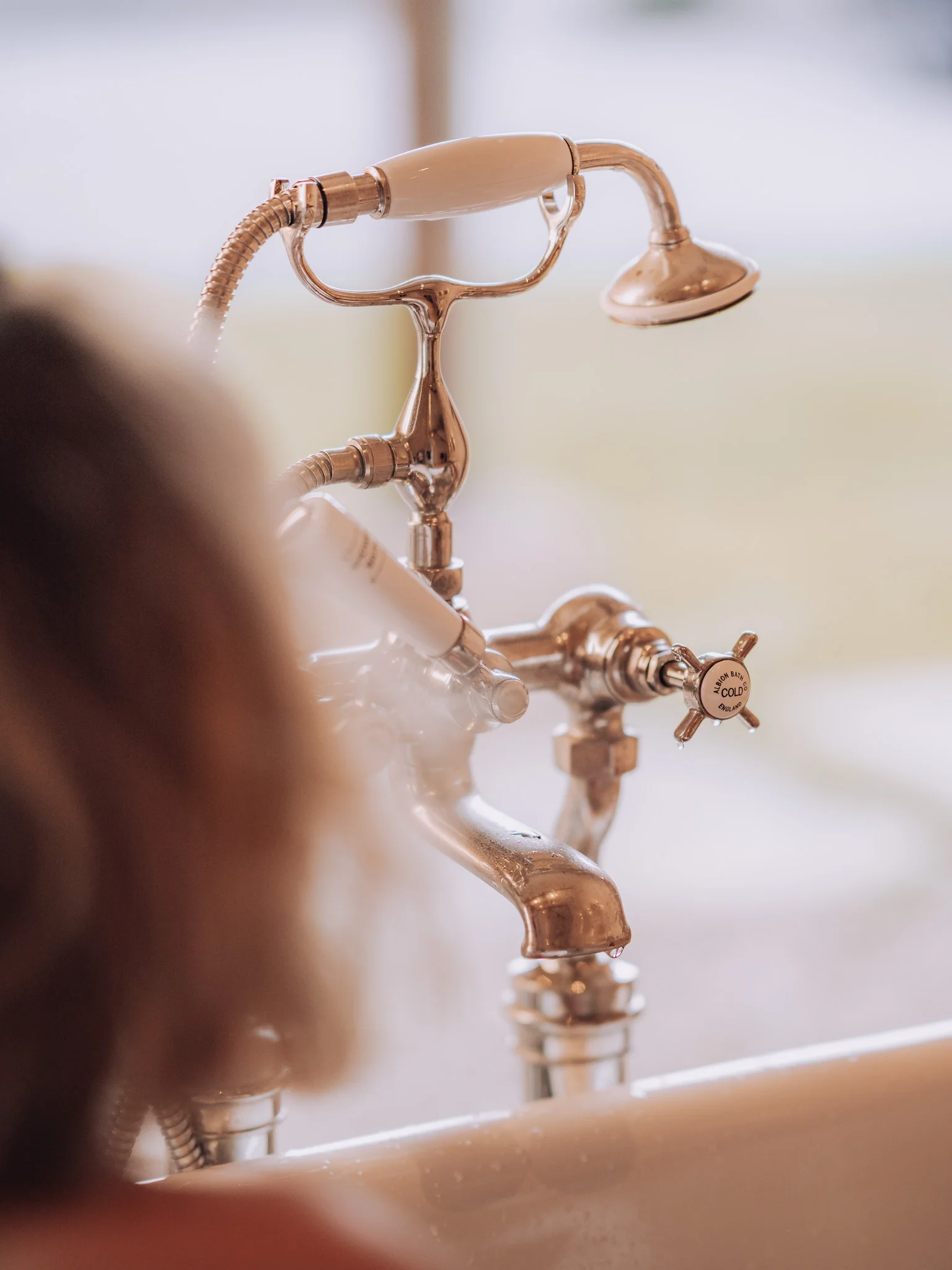 Woman relaxing in the bath at the Bull Pen at Bibury Farm Barns